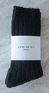 Pair of black socks with a 'Love of Ivy' label on a textured surface
