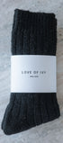 Pair of black socks with a 'Love of Ivy' label on a textured surface