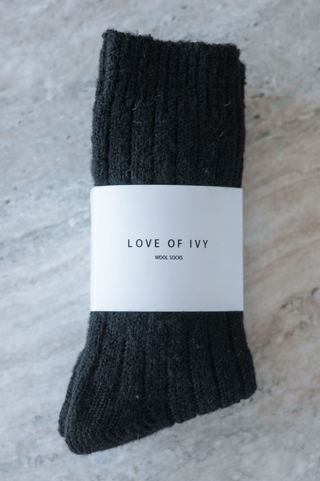 Pair of black socks with a 'Love of Ivy' label on a textured surface