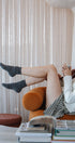 Person relaxing on a couch with feet up, surrounded by books and a magazine.