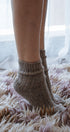 Person wearing brown knitted socks on a fluffy carpet