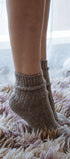 Person wearing brown knitted socks on a fluffy carpet