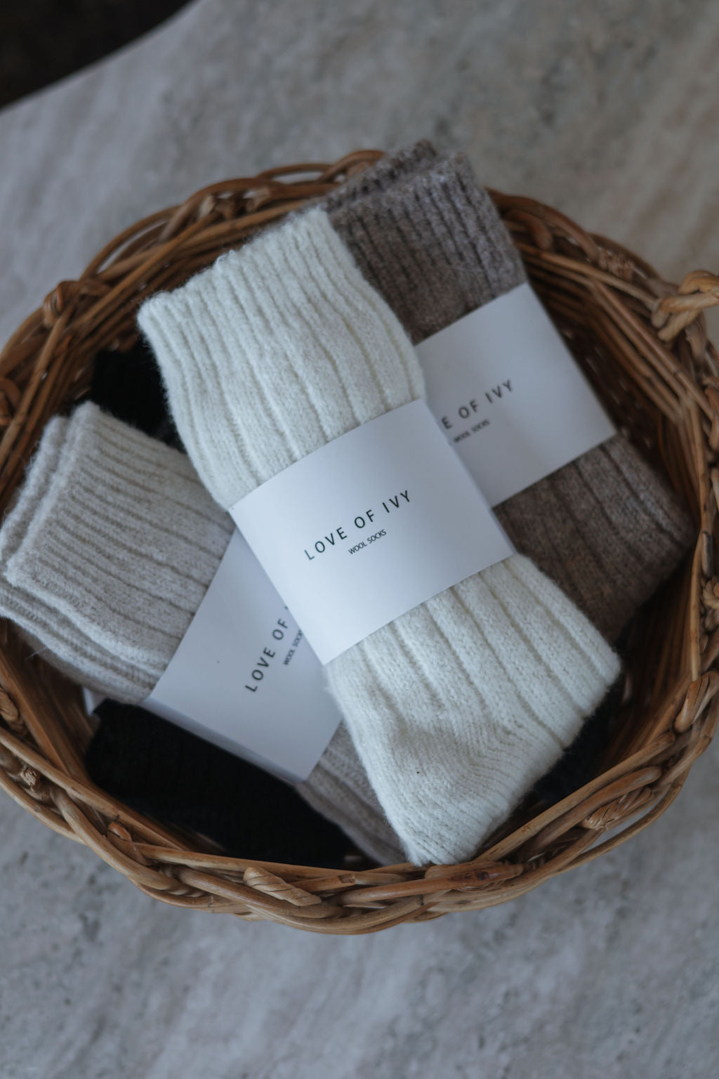 Three pairs of socks in a wicker basket with 'Love of Ivy' labels.