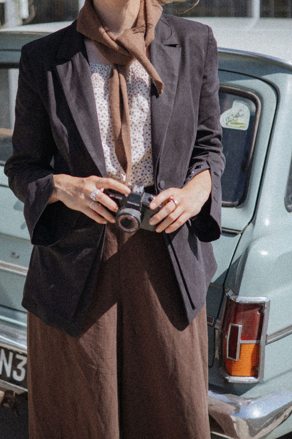Person holding a camera with a vintage car in the background